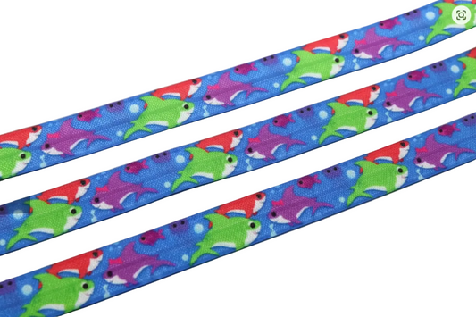 A close-up of a blue hearing aid headband featuring a colourful pattern of cartoon sharks in green, red, and purple.