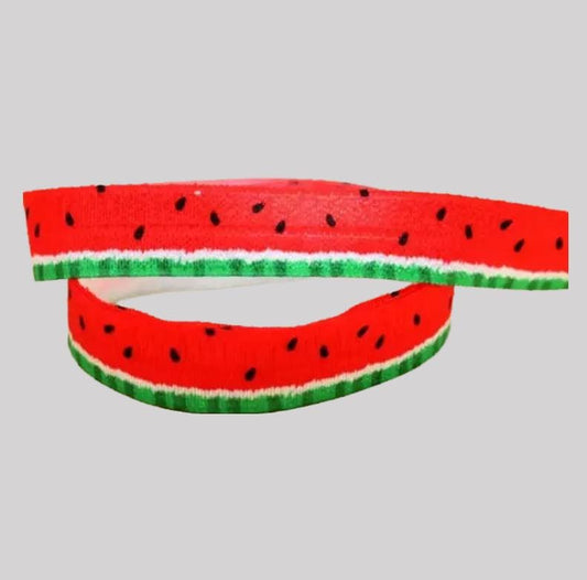 A red and green watermelon-shaped headband with black seeds on a plain background.