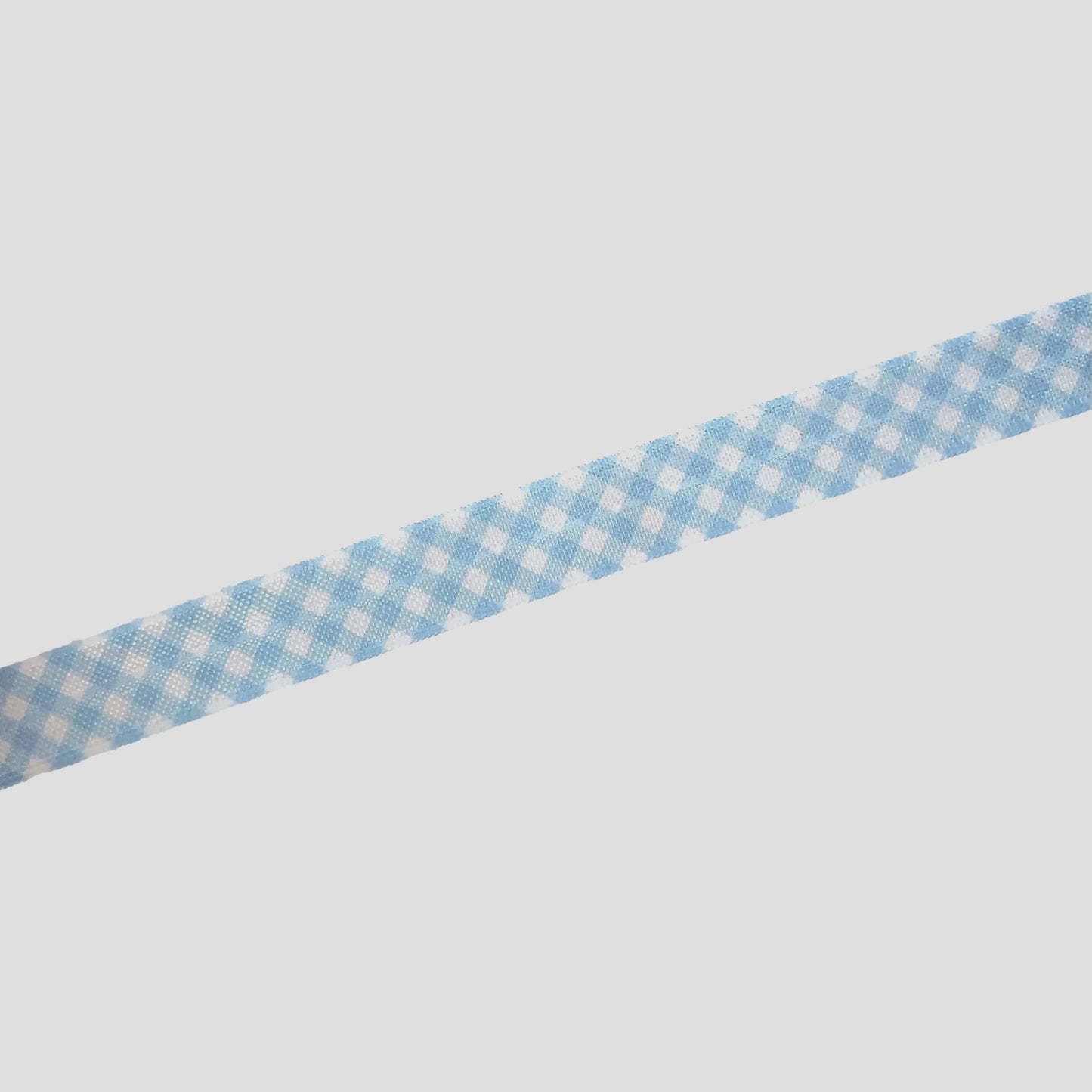 A blue and white checkered ribbon is lying on a white surface.