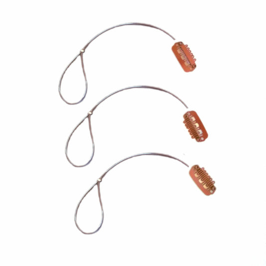 Three BAHA retaining lines with brown wig clip on a white background