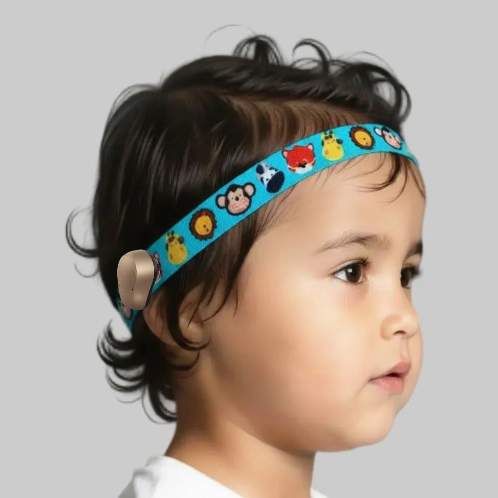 A close-up side profile of a young child wearing a bright blue elastic hearing aid headband decorated with cartoon animal faces.