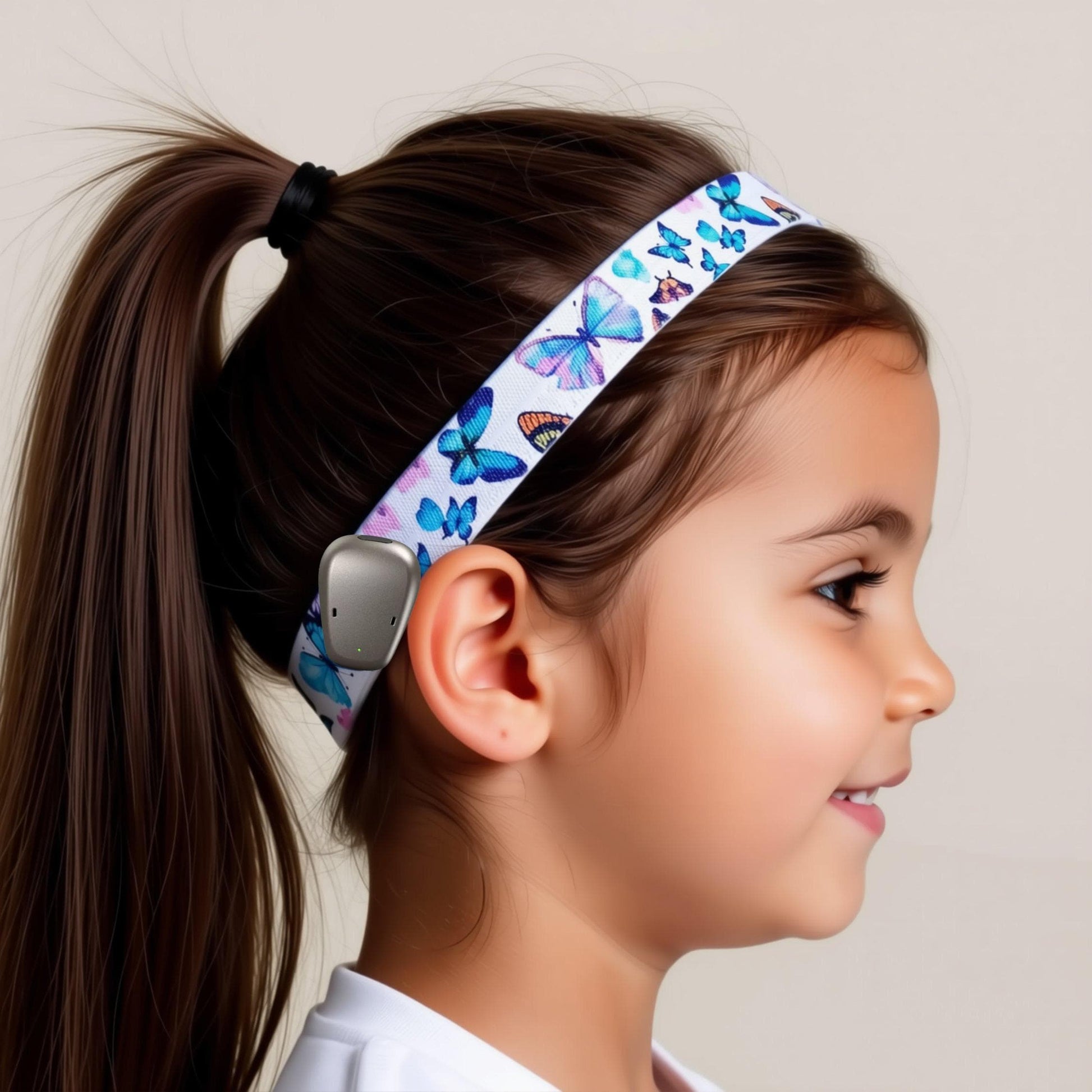a colourful butterfly-themed ponto Softband hearing aid headband, worn by a young child with brown hair in a pony tail