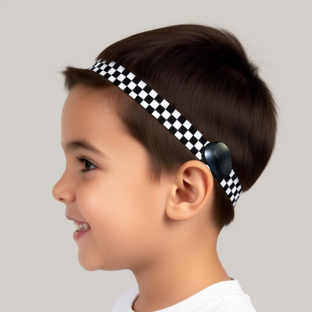 A young boy with short brown hair wearing a black and white checkered Ponto BAHA softband hearing aid cochlear implant headband.