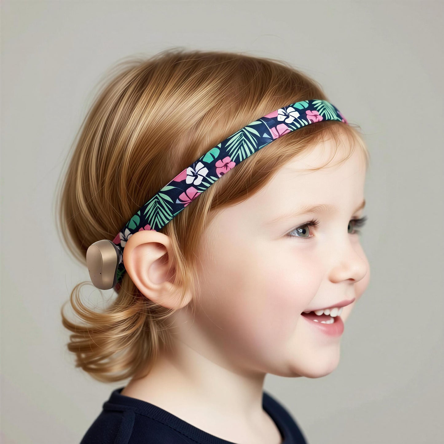 A young child with blonde hair wearing a floral headband Ponto BAHA bone-conduction hearing aid, shown in profile against a neutral gray background.