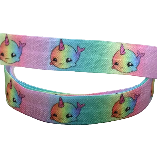 Ponto Baha softband hearing aid headband cochlear implant featuring a cute cartoon unicorn whale pattern, coiled on a wooden surface.