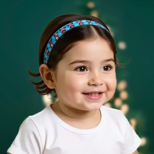 A smiling young girl with dark hair wearing a blue patterned cochlear implant hearing aid headband and a white t-shirt, set against a dark green background with soft bokeh lights.