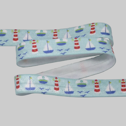 A light blue cochlear implant elastic with a nautical pattern featuring red and white lighthouses, white sailboats, and blue birds