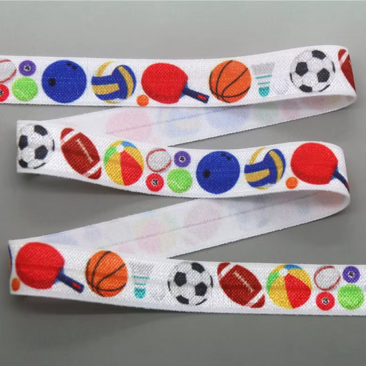 Ponto Baha softband hearing aid headband cochlear implant featuring a colourful sports-themed print with balls, paddles, and rackets, displayed on a neutral gray background.