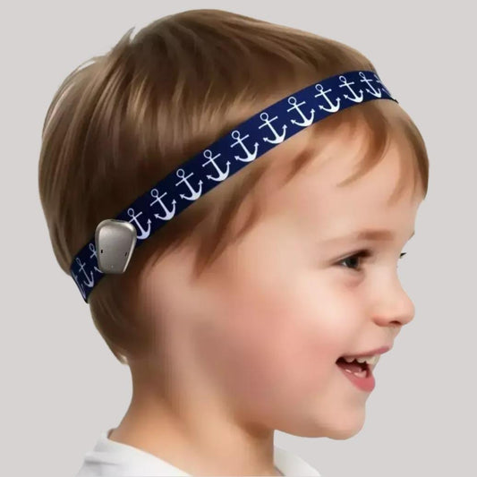A young child in profile wearing a navy blue headband with a repeating white anchor pattern and a ponto baha hearing aid, shown against a plain light gray background.