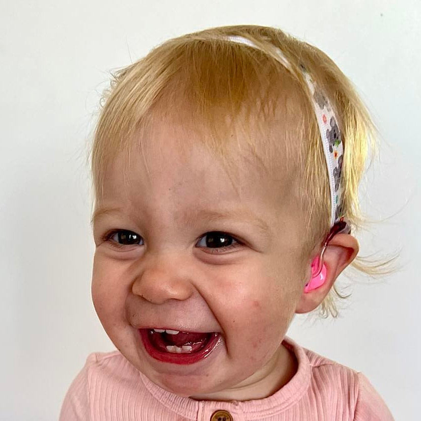 Child wearing a hearing aid headband with koalas.