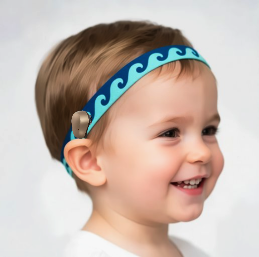 A close-up of a smiling young child wearing a blue and turquoise wave patterned ponto baha hearing aid headband