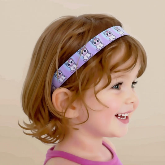 A young child with short auburn hair wearing a lavender headband with a repeating cartoon unicorn pattern, shown in profile against a soft beige background.