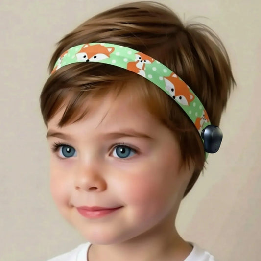 A young child wearing a light green ponto baha hearing aid headband with a fox pattern on green