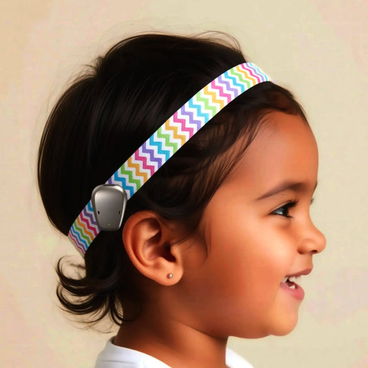 A young girl with dark hair wearing a colorful hearing aid headband with a zigzag pattern.