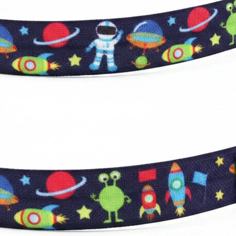 A close-up of a dark navy blue grosgrain ribbon featuring a colorful space-themed pattern with astronauts, aliens, rockets, and planets.