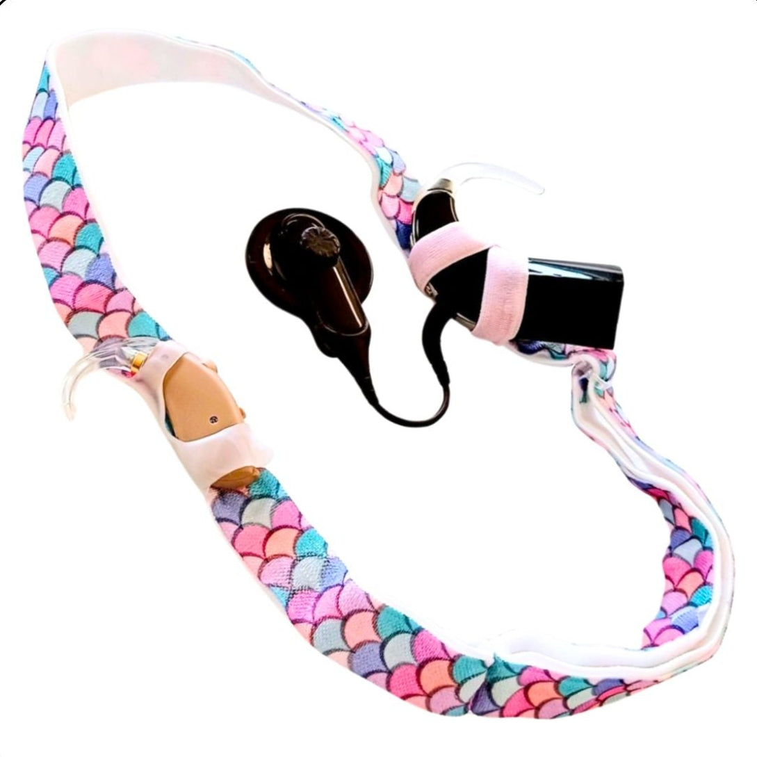 Colourful headband, printed with pastel colour mermaid scales, with cochlear implant and hearing aid attached
