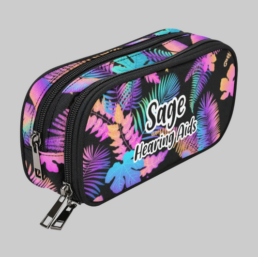 A rectangular zippered storage case for cochlear implants and hearing aids with a black background and a vibrant tropical leaf pattern in pink, purple, blue, and green. The front features the text 'Sage Hearing Aids' in white stylized lettering.