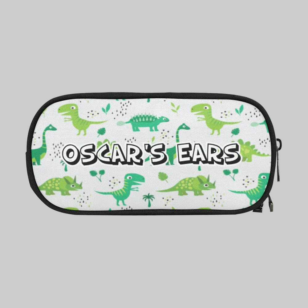 A rectangular zippered storage case pouch with rounded corners, for cochlear implant hearing aids Ponto BAHA devices, featuring a white background printed with green cartoon dinosaurs and the text 'OSCAR'S EARS' in bold white letters with black outlines. 