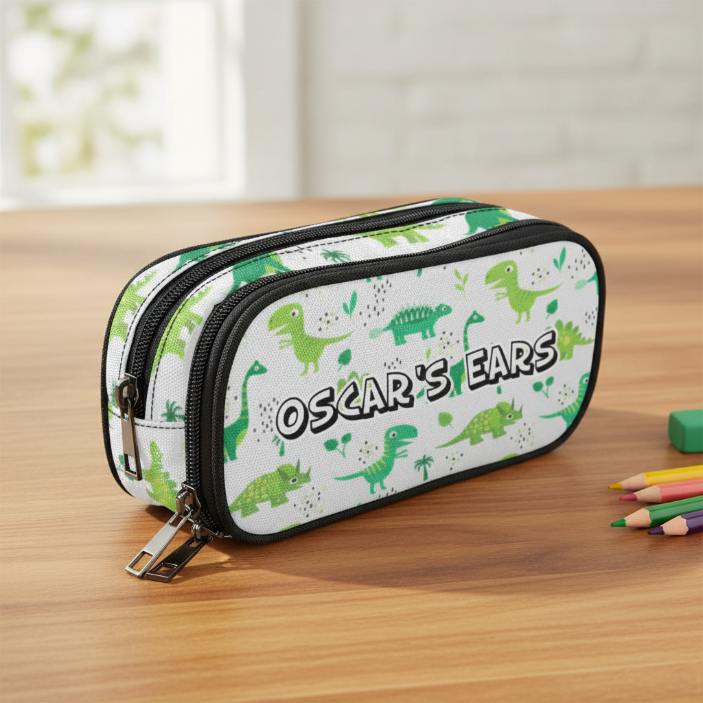 A white double-zipper storage case for cochlear implant hearing aid ponto baha devices featuring a green dinosaur pattern and the text 'OSCAR'S EARS' in black and white lettering