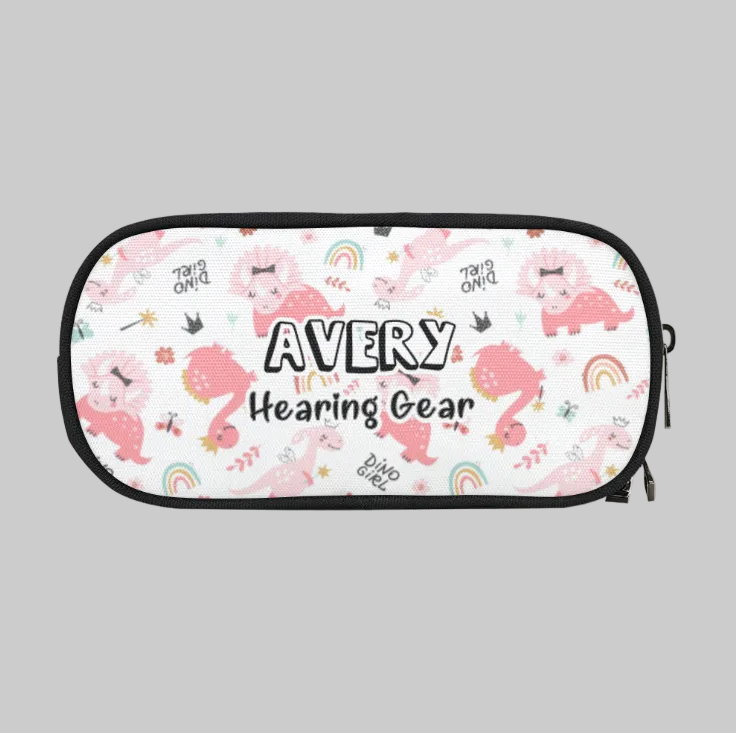 A white zippered storage case for cochlear implant hearing aids with a black border and a playful pink cartoon dinosaur pattern, featuring the text 'AVERY Hearing Gear' in the center.