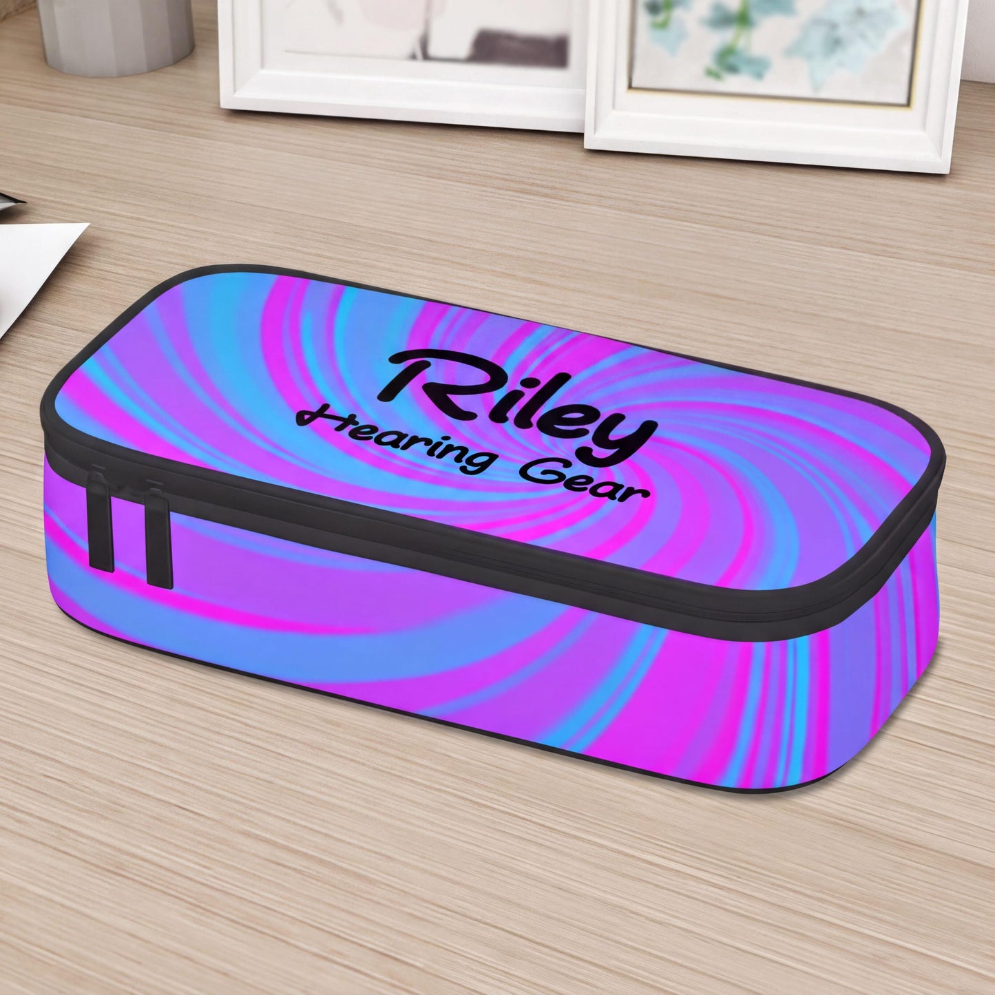 A colourful pouch case for cochlear implants or hearing aids with the name Riley Hearing Gear printed on it, sitting on a wooden surface.