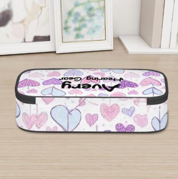 A rectangular zippered pouch for Ponto BAHA hearing aids or cochlear implants with a white background and a pattern of pink, purple, and light blue hearts, featuring the text 'Avery Hearing Gear' in black script. The pouch is placed on a light wood surface with framed pictures in the background.