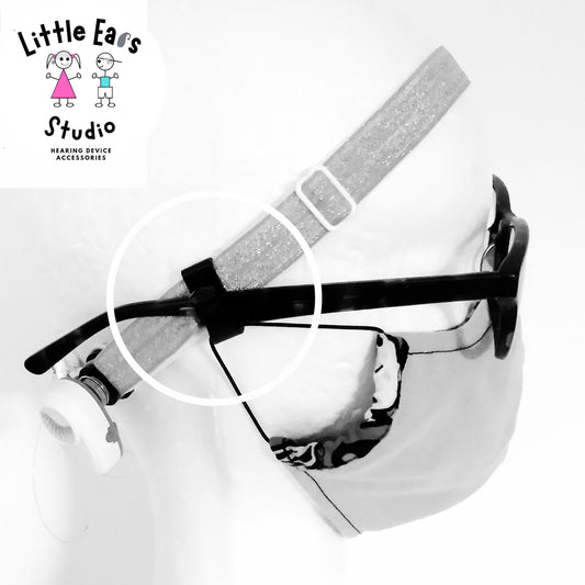 Hearing aid with a strap on a white background, branded 'Little Ears Studio'.