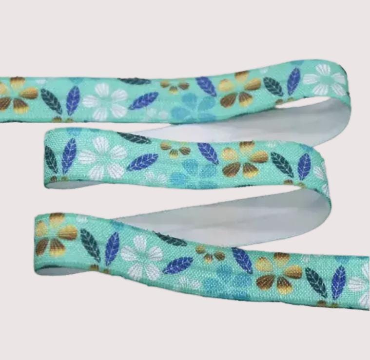 A turquoise ribbon with a floral pattern of white and blue flowers and leaves.